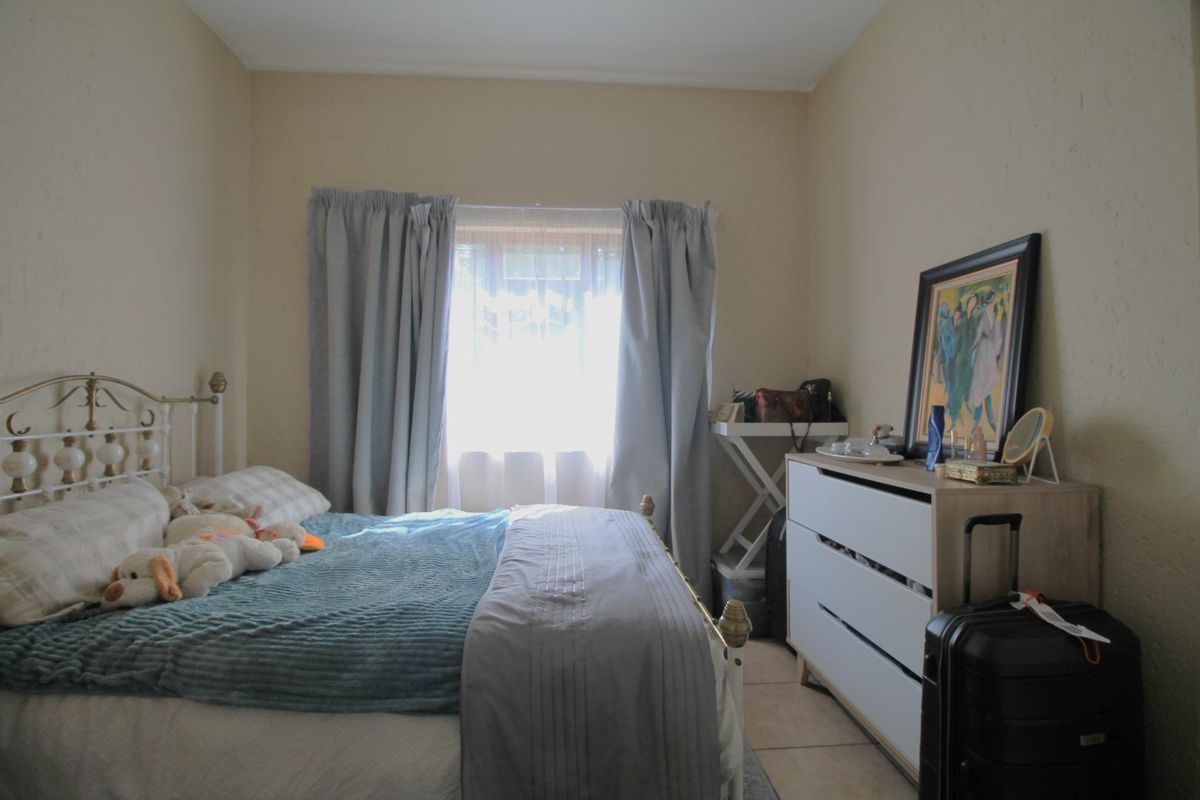 A functional bedroom featuring tiled flooring and a central window, providing a neutral base for personalization.