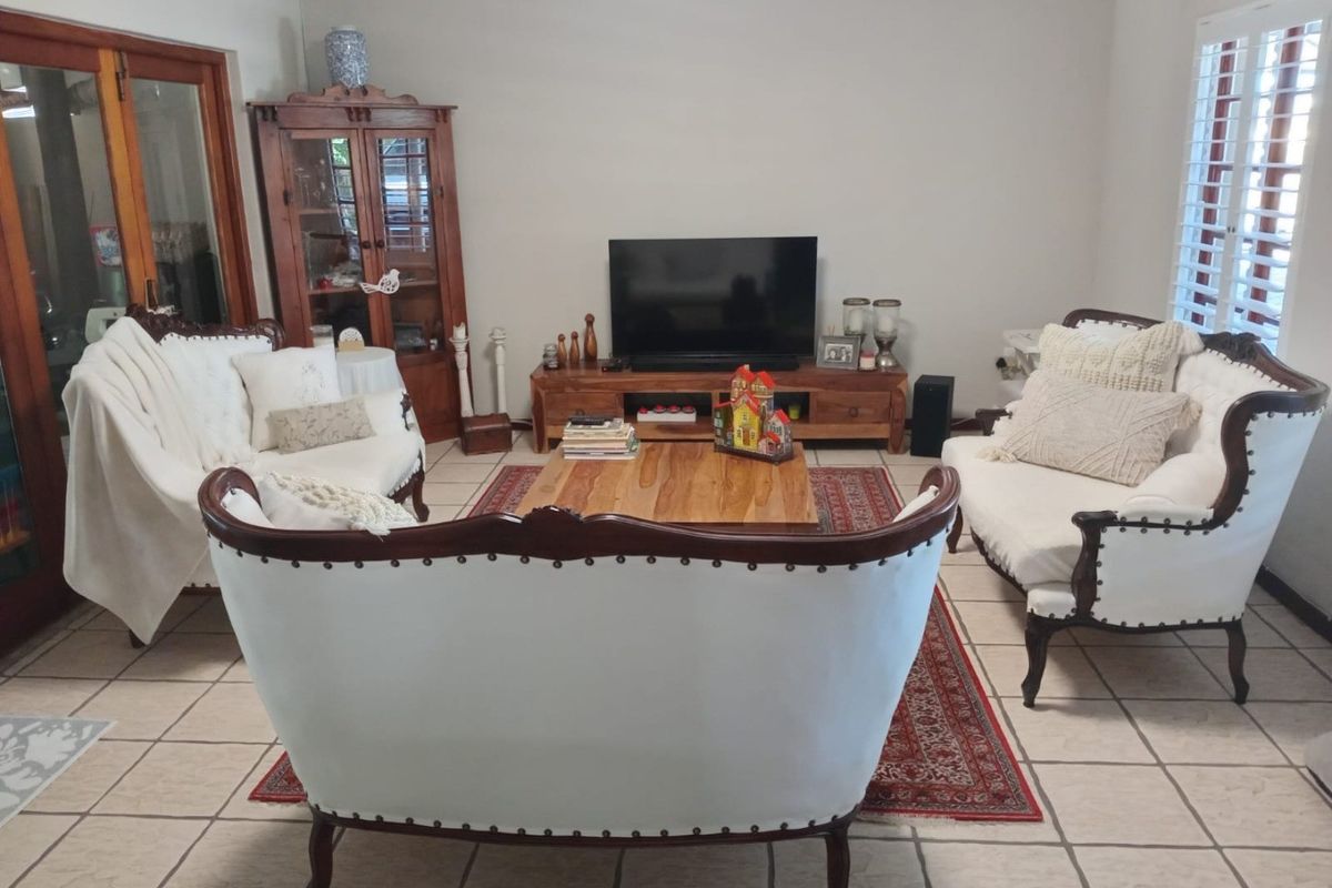 A comfortable living room featuring tiled flooring and classic wooden window shutters, providing a neutral foundation for various interior design styles.