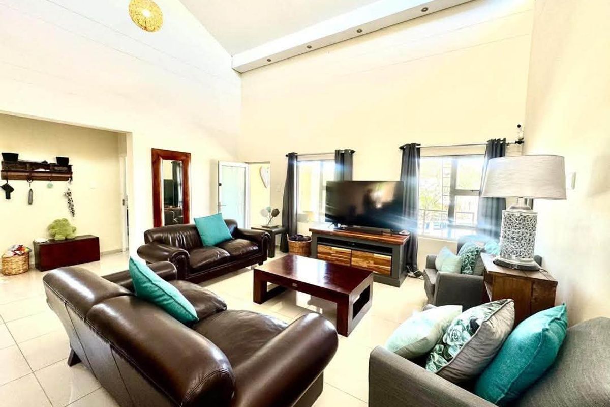 Spacious living room featuring high vaulted ceilings, tiled flooring, and abundant natural light from large windows, creating an open and airy atmosphere.