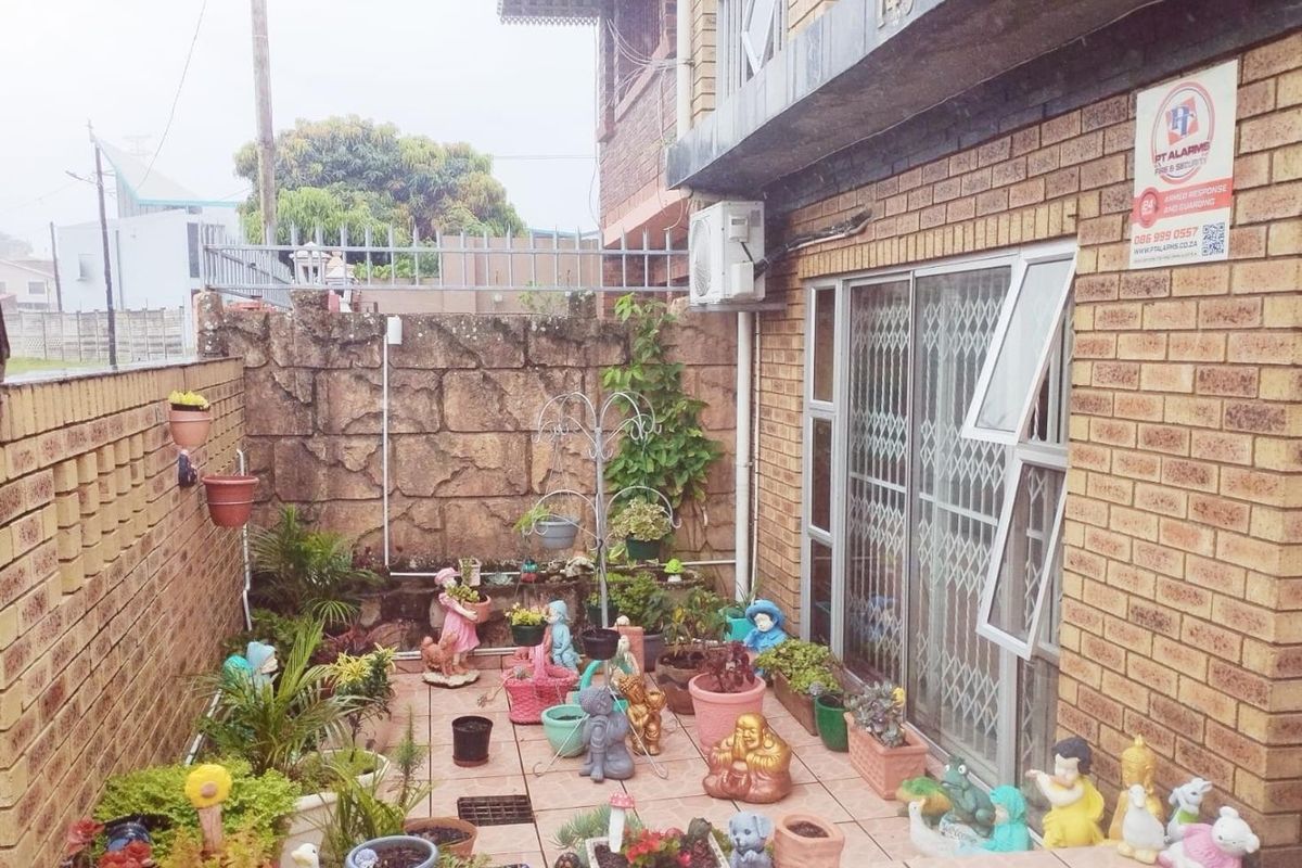 A private rear courtyard featuring brick wall boundaries, tiled flooring, and direct access to the home via a secure sliding door.