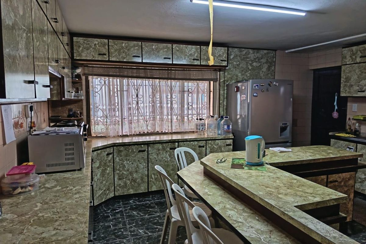 A dated kitchen featuring extensive laminate cabinetry, a breakfast bar, and tiled flooring, offering significant potential for a modern renovation.