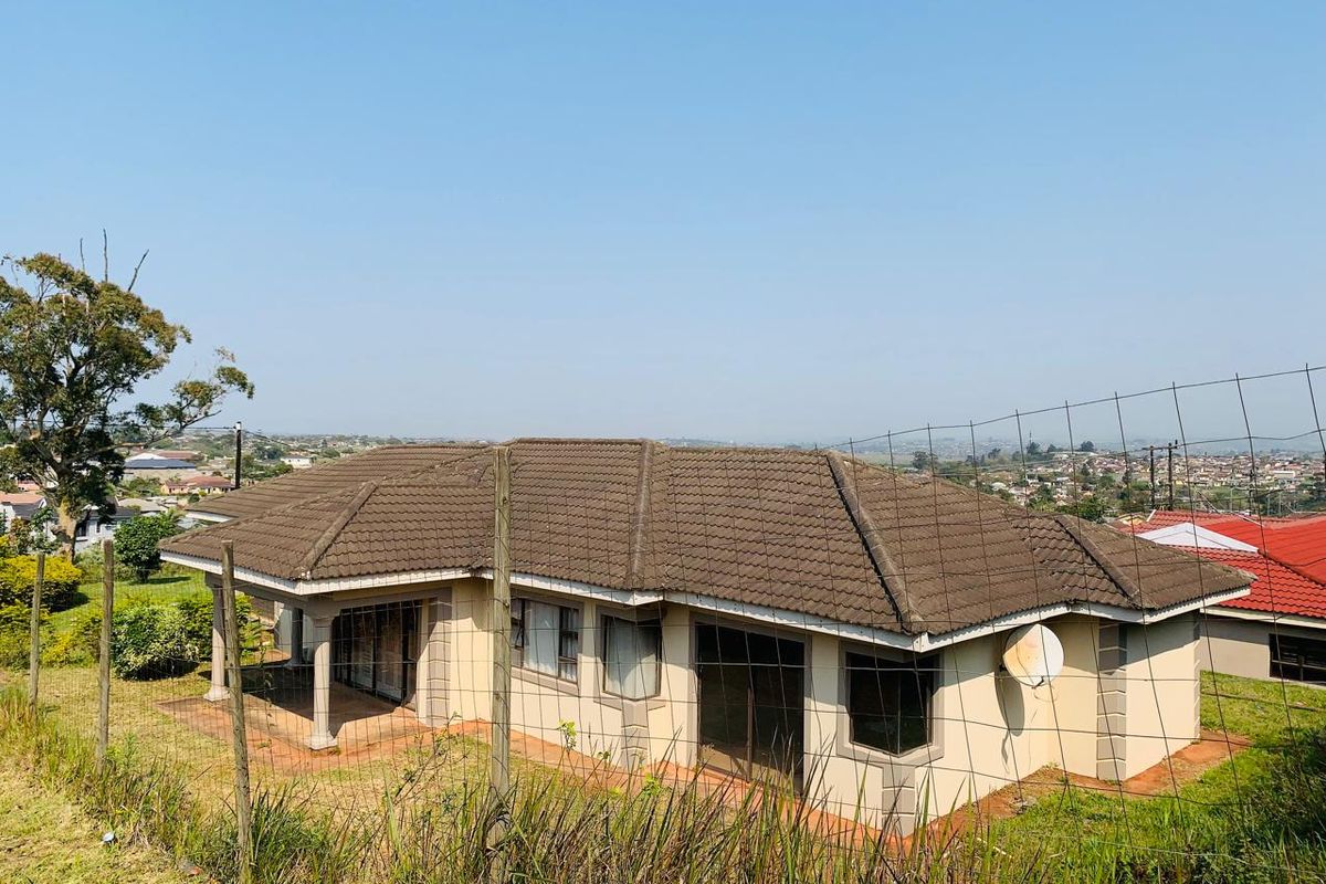 Rear view of a single-story residential house featuring a covered patio, sliding glass doors, and concrete roof tiles, set in a suburban landscape.
