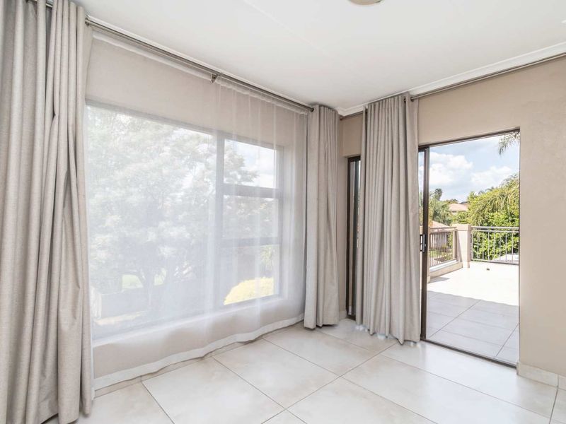 Bright and spacious living area featuring neutral tiled flooring, large windows, and direct access to an outdoor balcony through a sliding glass door.