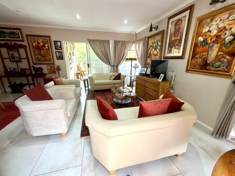 A well-maintained living room featuring large format floor tiles, recessed lighting, and a sliding glass door providing access to the outdoor area.