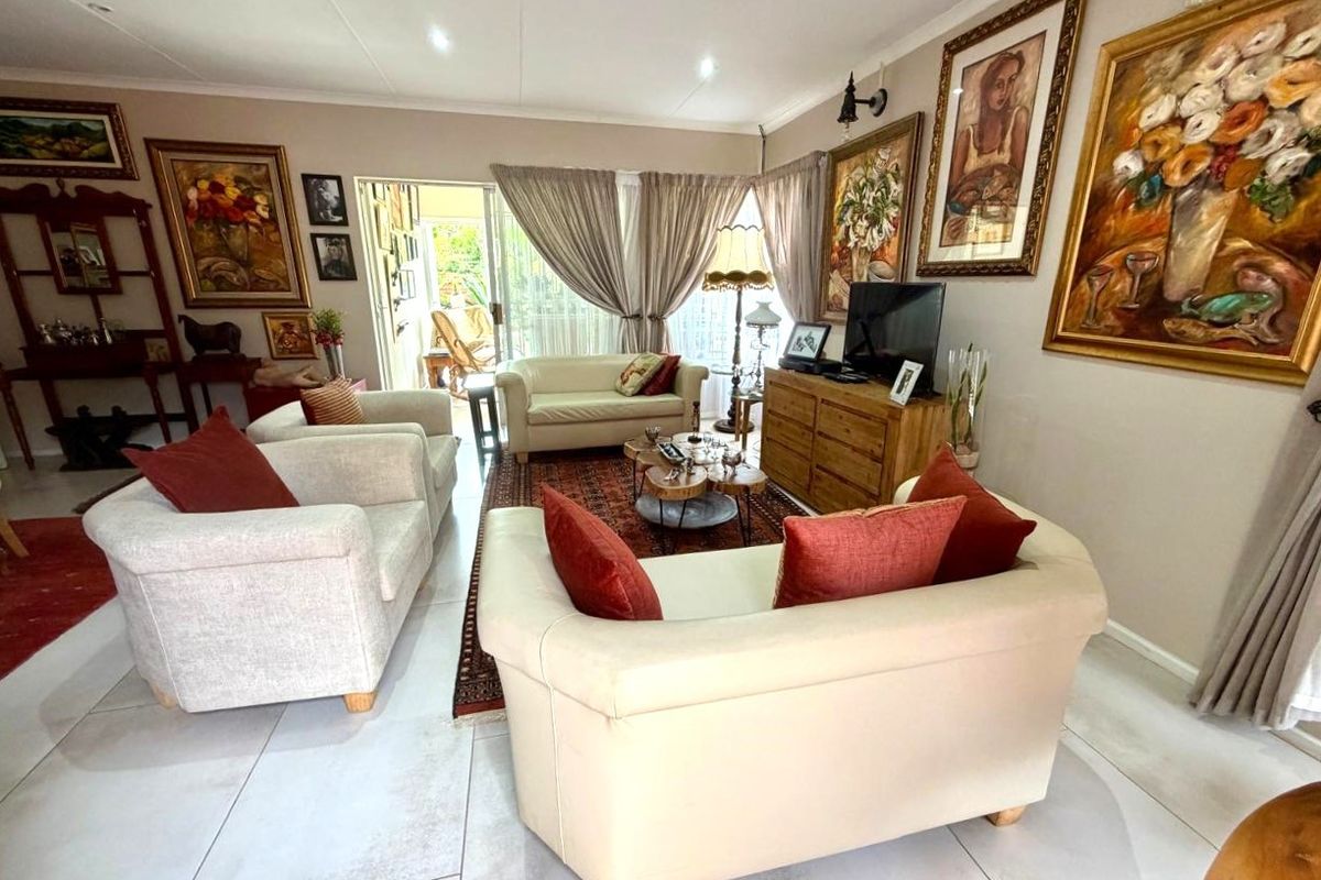 A well-maintained living room featuring large format floor tiles, recessed lighting, and a sliding glass door providing access to the outdoor area.