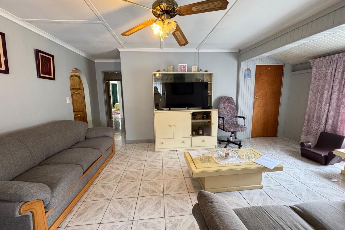 A living room featuring tiled flooring, a ceiling fan, and an arched doorway leading to adjacent rooms.