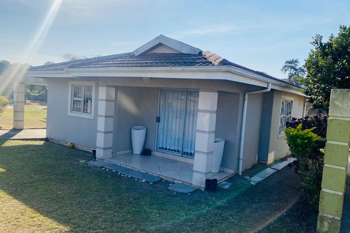 A rear view of the townhouse featuring a covered tiled patio, sliding glass doors with security gates, and a pitched tiled roof.