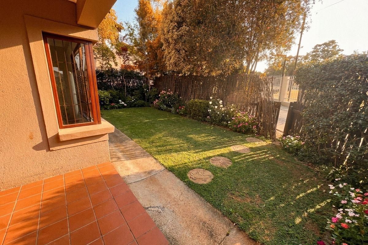 A private rear garden featuring a tiled patio area, a well-maintained lawn, and established perimeter fencing.