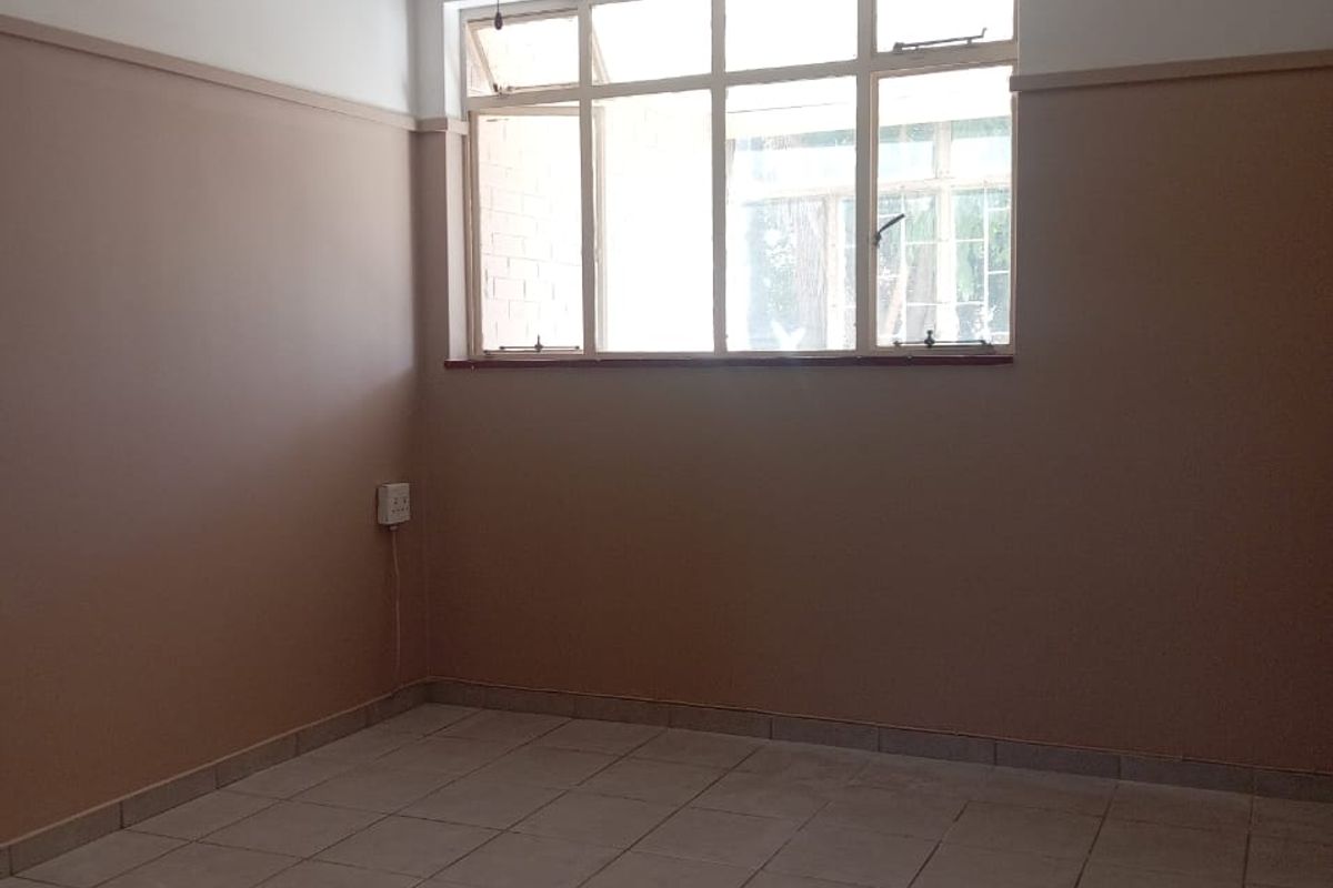 An empty bedroom featuring tiled flooring, a ceiling fan, and a large multi-pane window, offering a neutral canvas for personalization.