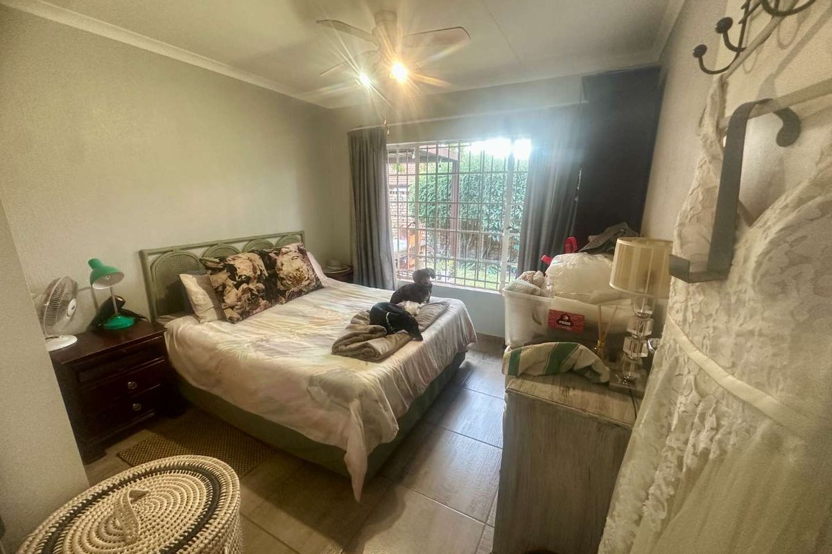 A functional bedroom featuring tiled flooring, a ceiling fan, and security bars on the window, providing a secure and practical living space.