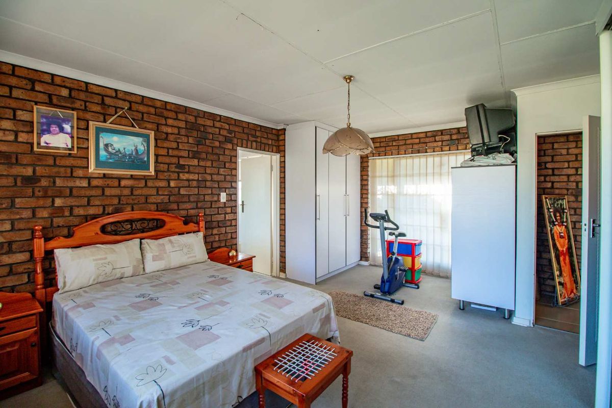 A bedroom featuring an exposed brick feature wall, built-in wardrobe, and neutral carpeting.