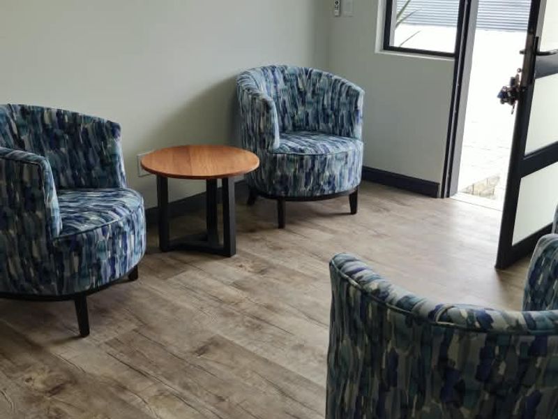 A bright living area featuring wood-look laminate flooring, neutral walls, and a glass-paneled door providing access to the exterior.