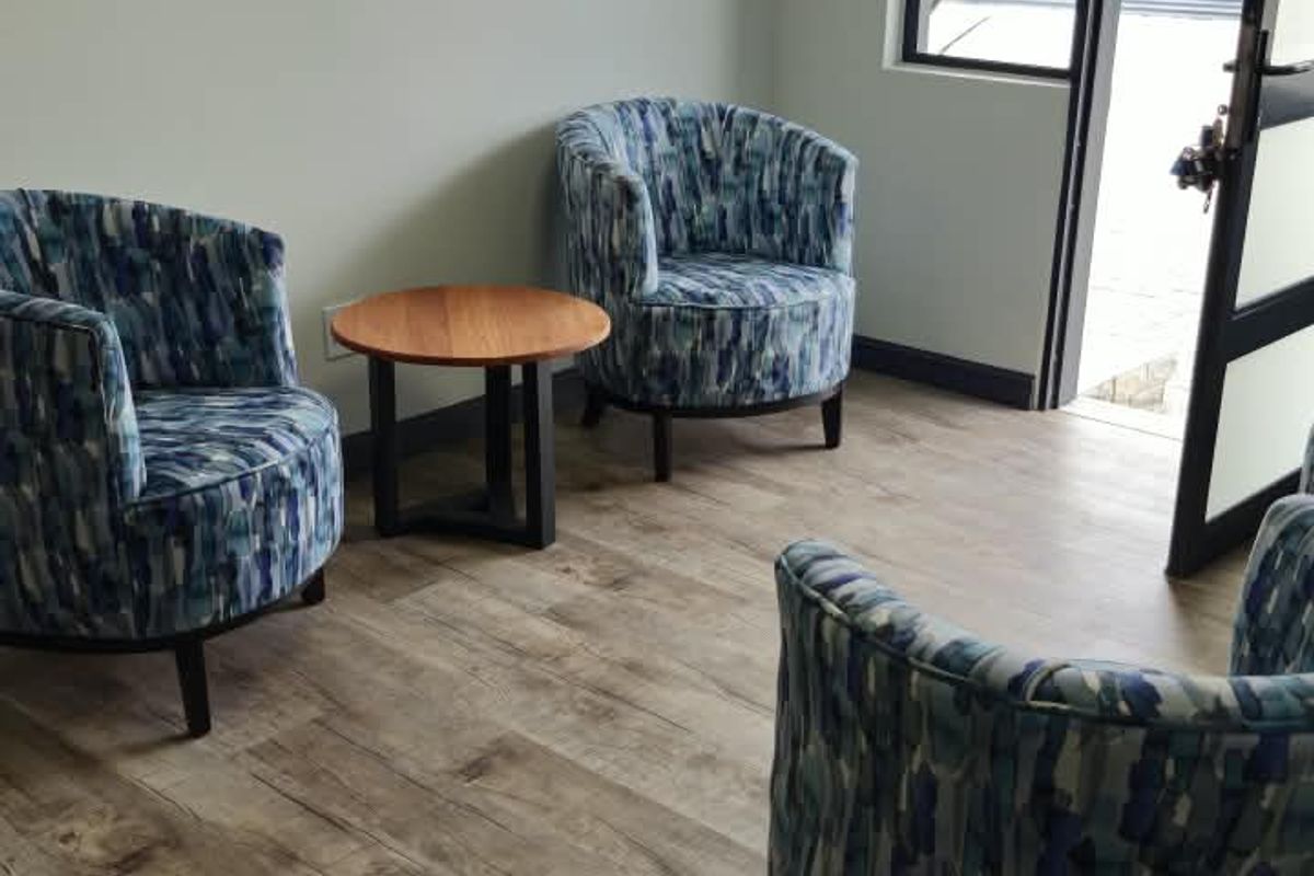 A bright living area featuring wood-look laminate flooring, neutral walls, and a glass-paneled door providing access to the exterior.