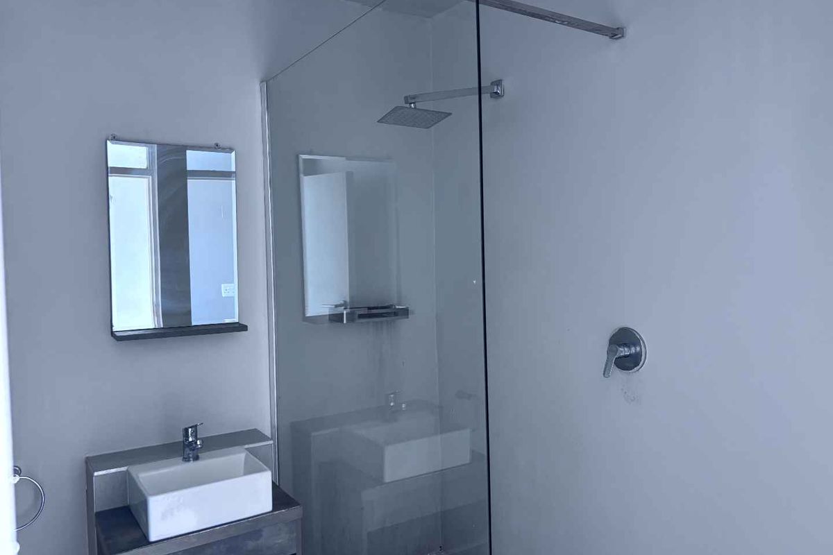 Modern bathroom featuring a vessel sink with vanity, a glass-enclosed walk-in shower with a rain shower head, and a wall-mounted mirror.