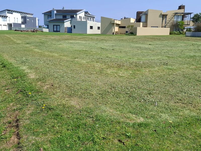 A level, well-maintained vacant residential plot featuring a paved driveway and established grass lawn in a developed neighborhood.