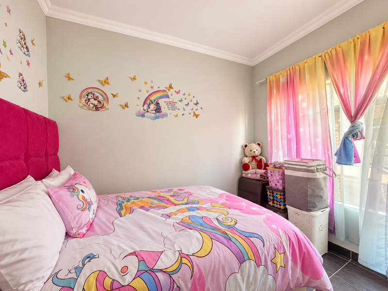 A bright bedroom featuring crown molding and tiled flooring, currently styled as a children's room with ample natural light.
