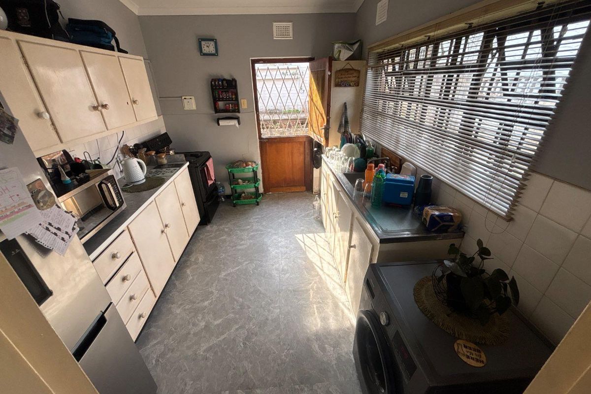 Functional kitchen featuring built-in cabinetry, laminate countertops, tiled splashback, and direct access to the exterior via a security door.