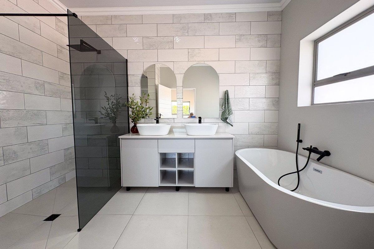 Modern bathroom featuring a double vanity, freestanding bathtub, and a spacious walk-in shower with a glass screen and contemporary black fixtures.