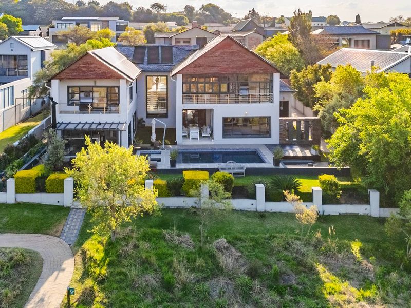 Aerial view of a modern double-story residence featuring a swimming pool, spacious rear patio, balcony, and well-maintained landscaped garden.