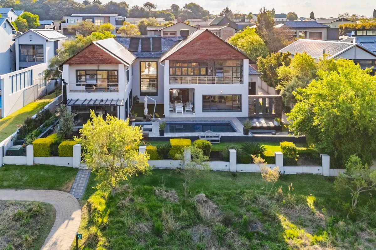 Aerial view of a modern double-story residence featuring a swimming pool, spacious rear patio, balcony, and well-maintained landscaped garden.