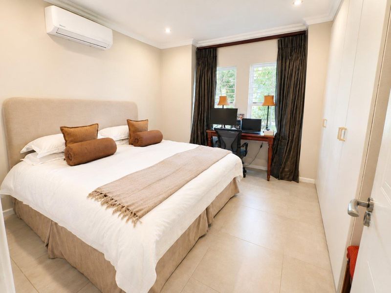 A well-maintained bedroom featuring tiled flooring, built-in cupboards, and a split-system air conditioner, offering a comfortable and functional living space.