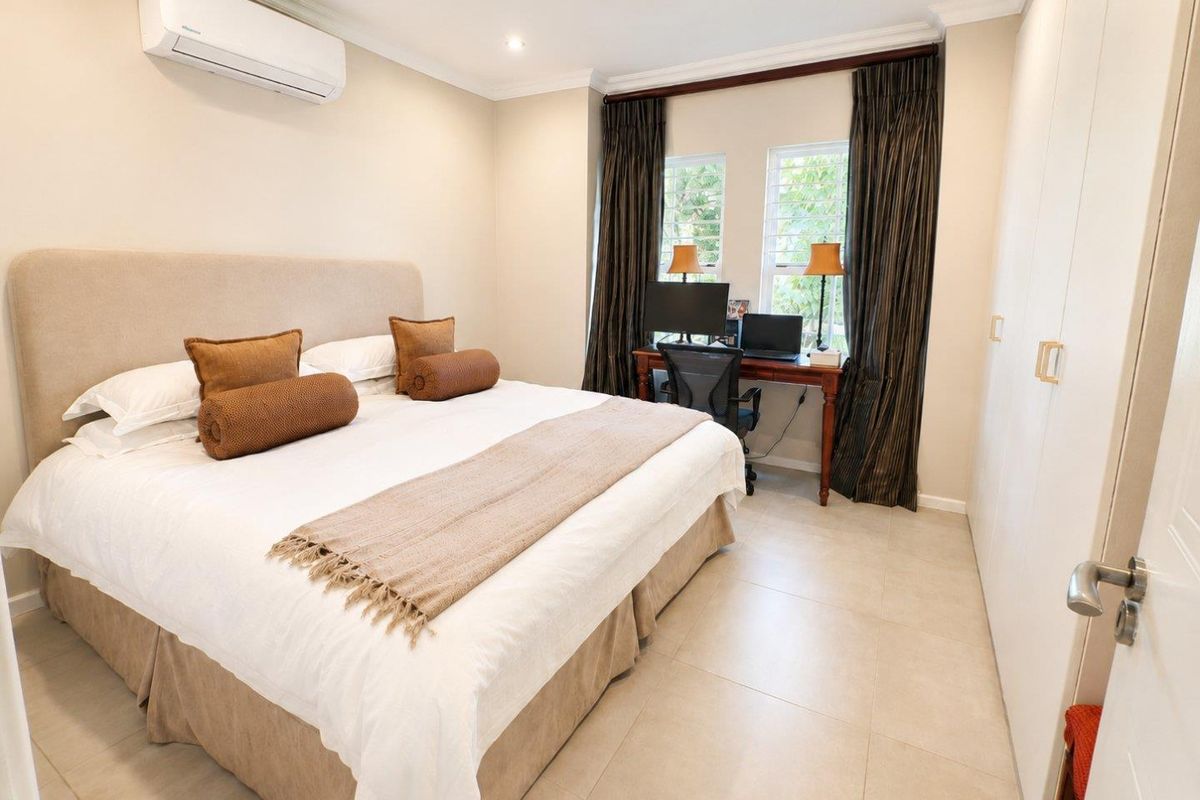 A well-maintained bedroom featuring tiled flooring, built-in cupboards, and a split-system air conditioner, offering a comfortable and functional living space.