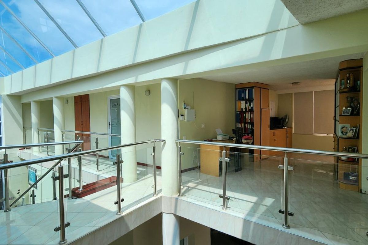 Spacious upper-level landing featuring a large glass skylight, modern stainless steel and glass balustrades, and tiled flooring.