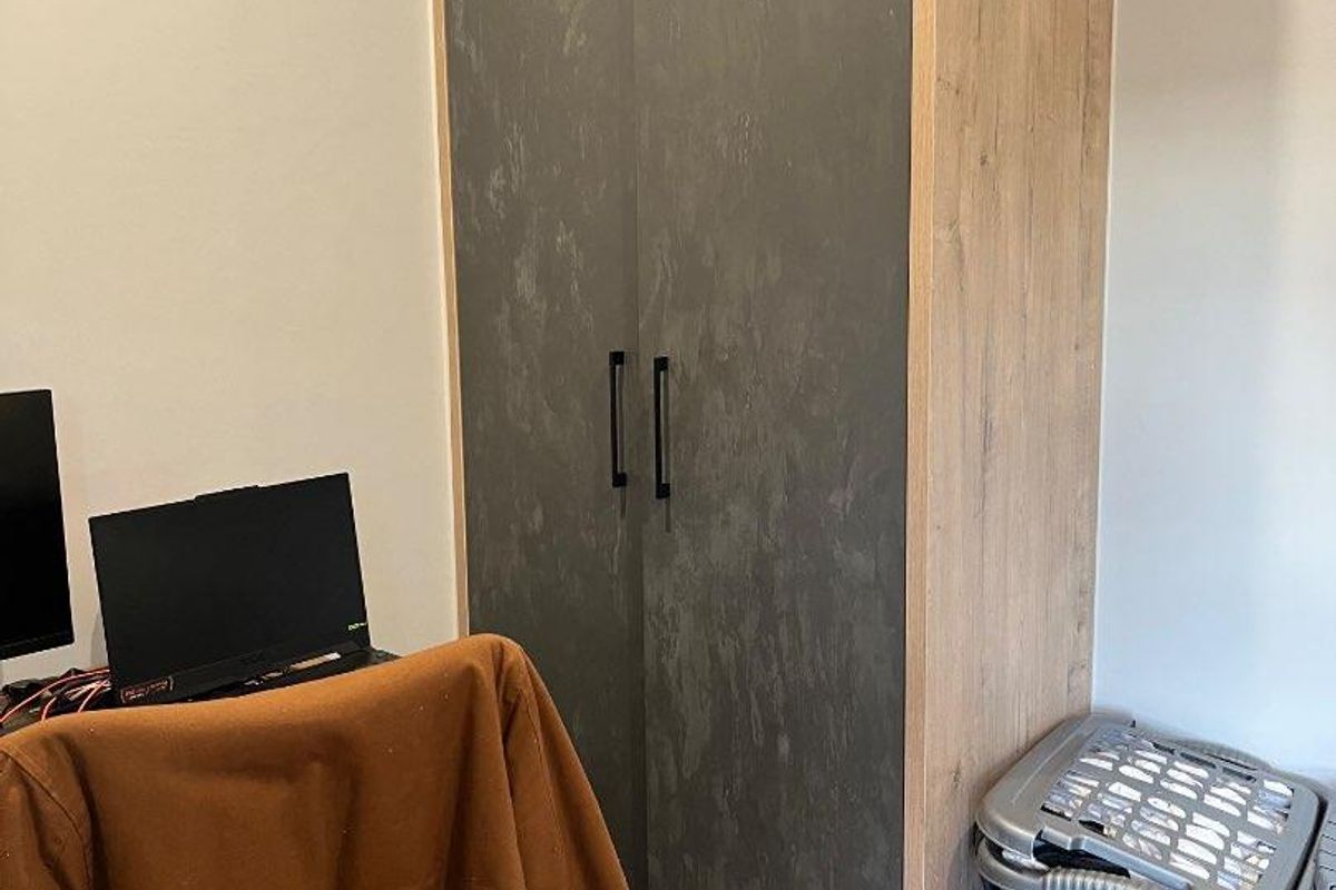 A bedroom featuring a built-in wardrobe with a modern wood-grain and textured grey finish.