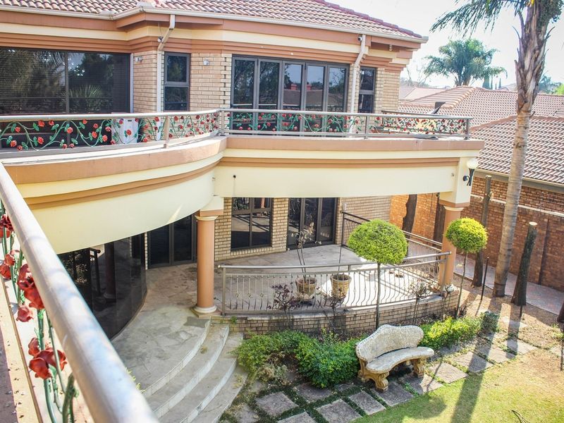 Rear view of the house featuring a spacious upper balcony and a covered ground-floor patio overlooking the garden area.