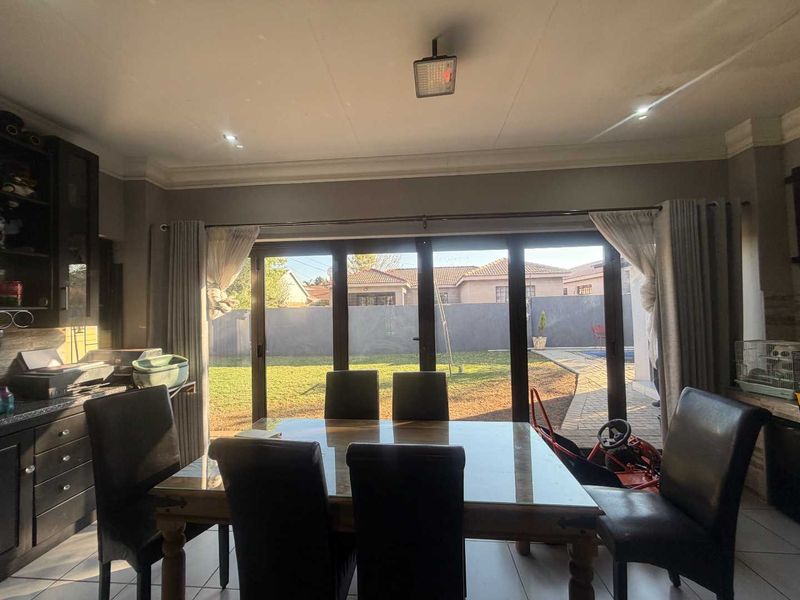 Dining room featuring tiled flooring, built-in cabinetry, and large sliding glass doors providing direct access to the rear garden and patio area.