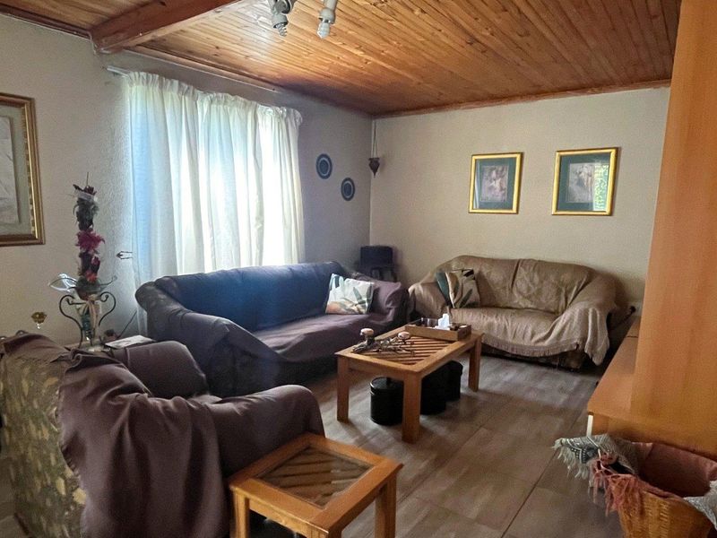 A cozy living room featuring a warm timber tongue and groove ceiling and neutral tiled flooring, offering a comfortable and inviting atmosphere.