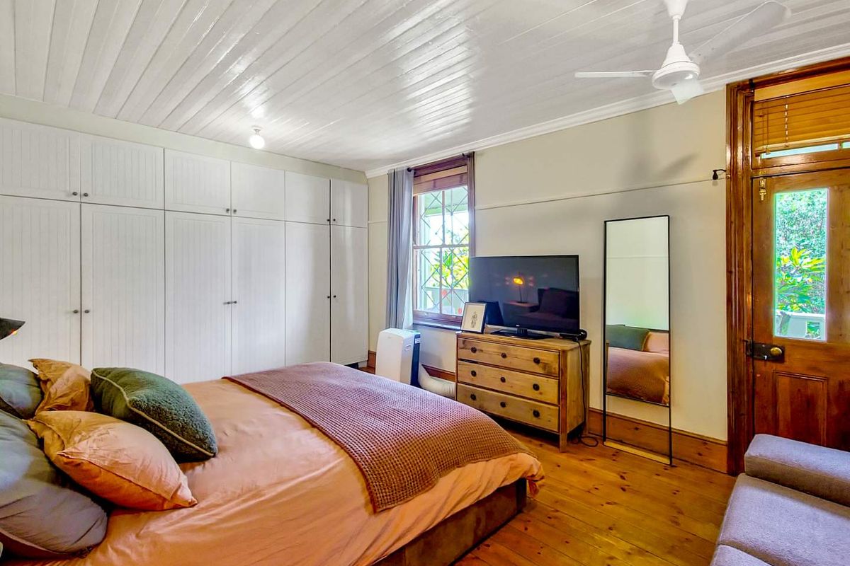 A bedroom featuring timber flooring, a white tongue-and-groove ceiling, a ceiling fan, and extensive built-in wardrobe storage.
