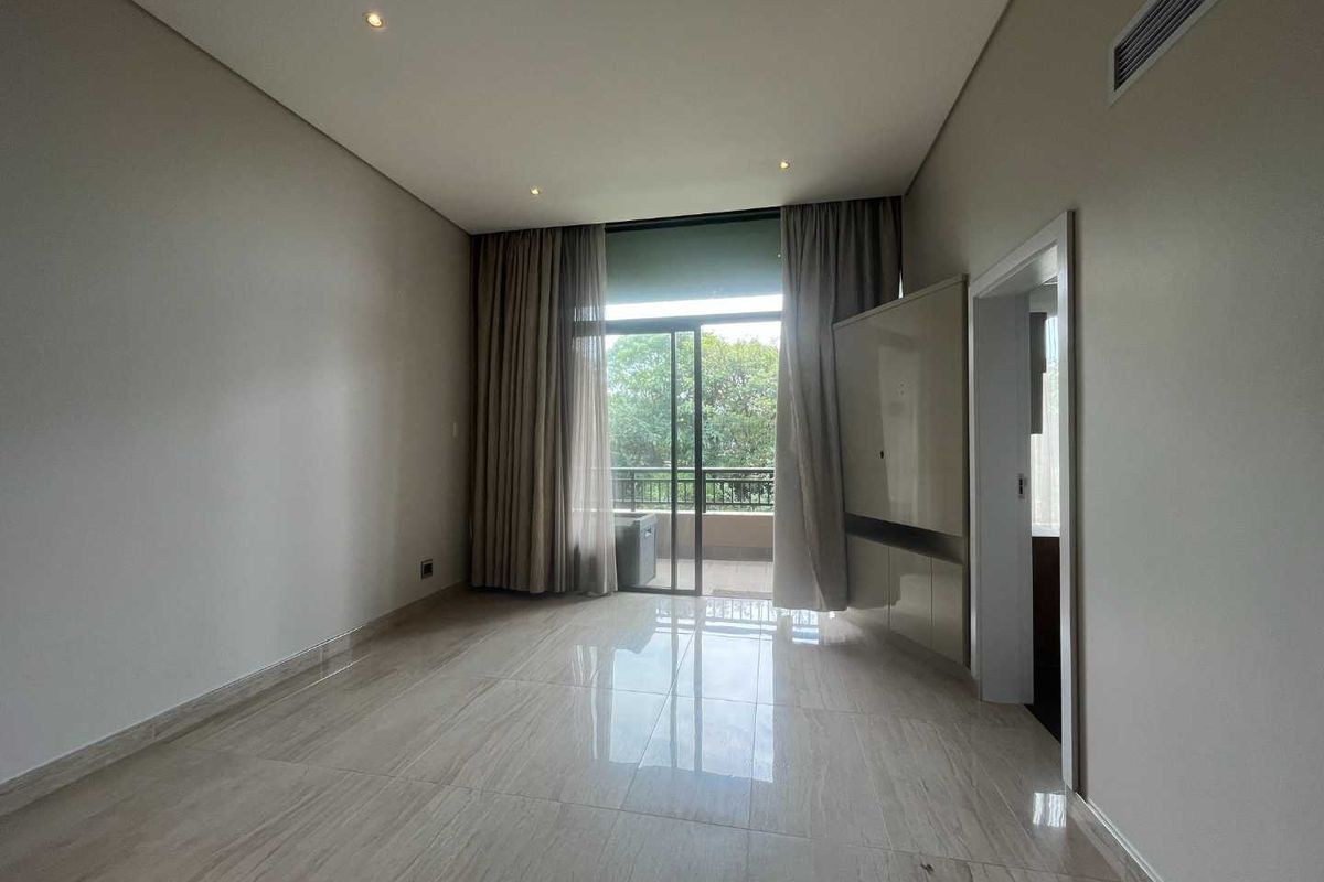 A bright, modern bedroom featuring polished tile flooring, recessed ceiling lighting, integrated air conditioning, and sliding glass doors leading to a private balcony.