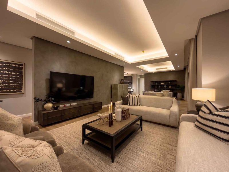 A modern, well-appointed living room featuring recessed ceiling lighting, ducted air conditioning, and a sophisticated feature wall with high-quality finishes.