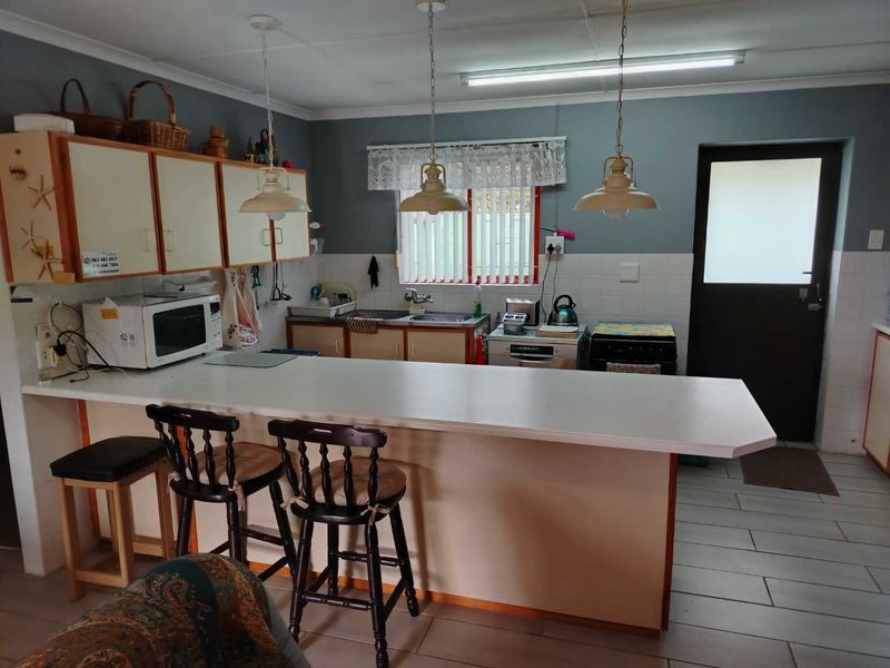 A functional kitchen featuring a breakfast bar, ample cabinetry, double sink, and direct access to the exterior, offering potential for modern cosmetic updates.