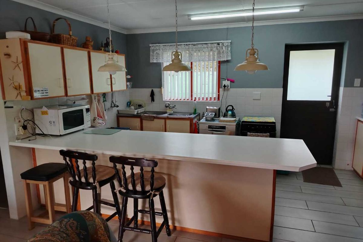 A functional kitchen featuring a breakfast bar, ample cabinetry, double sink, and direct access to the exterior, offering potential for modern cosmetic updates.