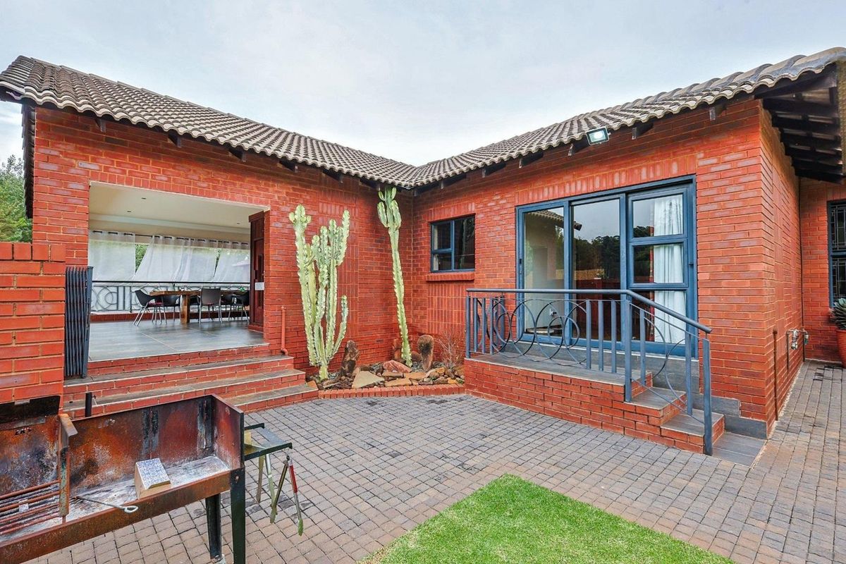 A private rear courtyard featuring red brick construction, paved flooring, and direct access to a covered patio and interior living spaces.