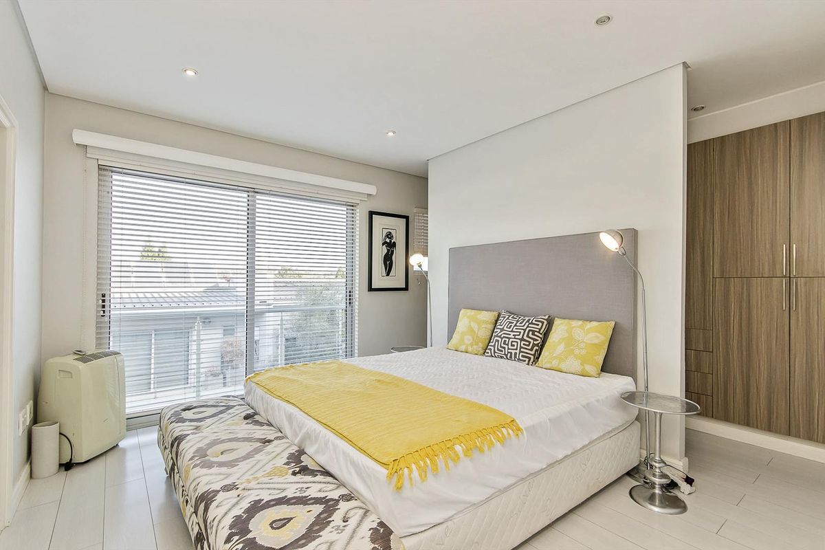 A well-maintained bedroom featuring built-in wooden cabinetry, recessed ceiling lighting, and large sliding glass doors with integrated blinds.
