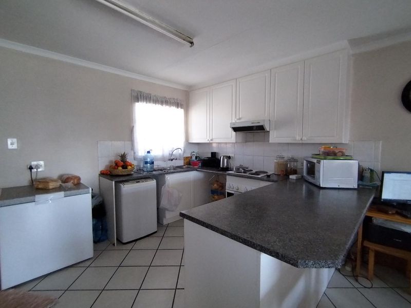 A functional kitchen featuring white cabinetry, laminate countertops, tiled flooring, and a tiled backsplash, offering a practical layout for daily meal preparation.