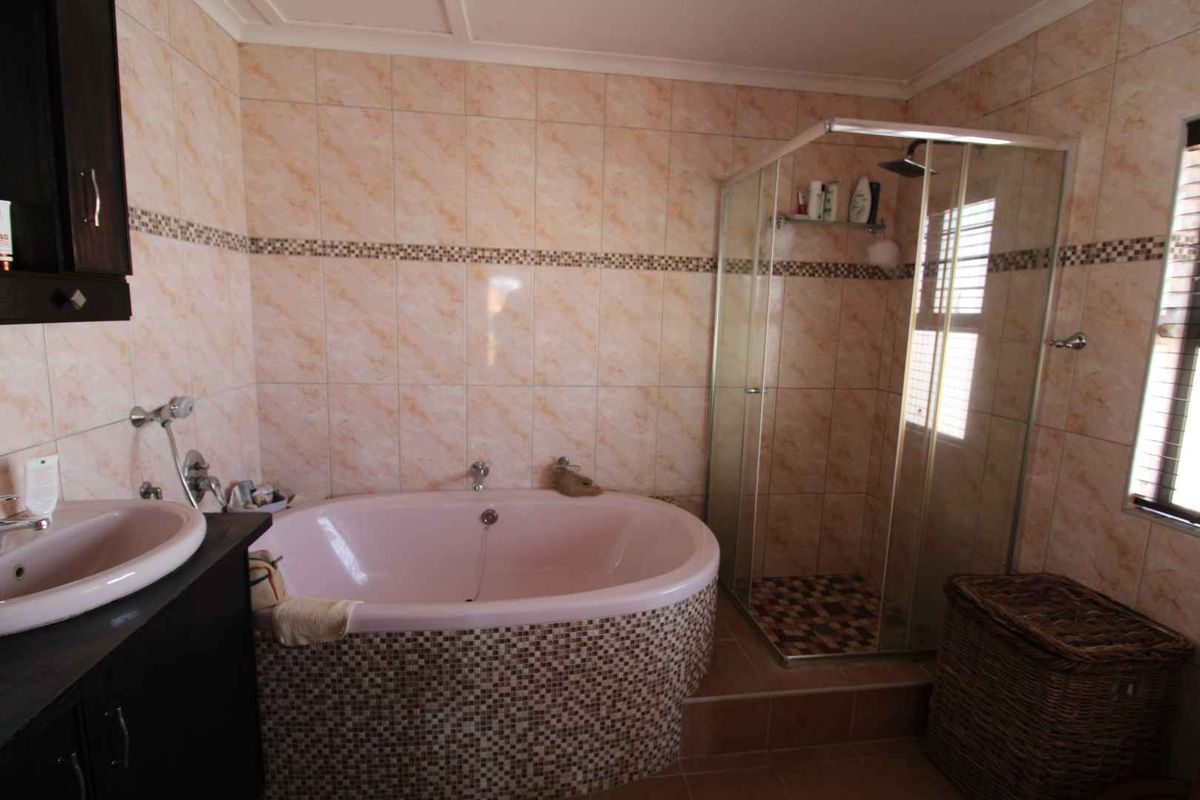 A bathroom featuring a built-in bathtub with mosaic tiling, a separate glass-enclosed shower, and a vanity basin.