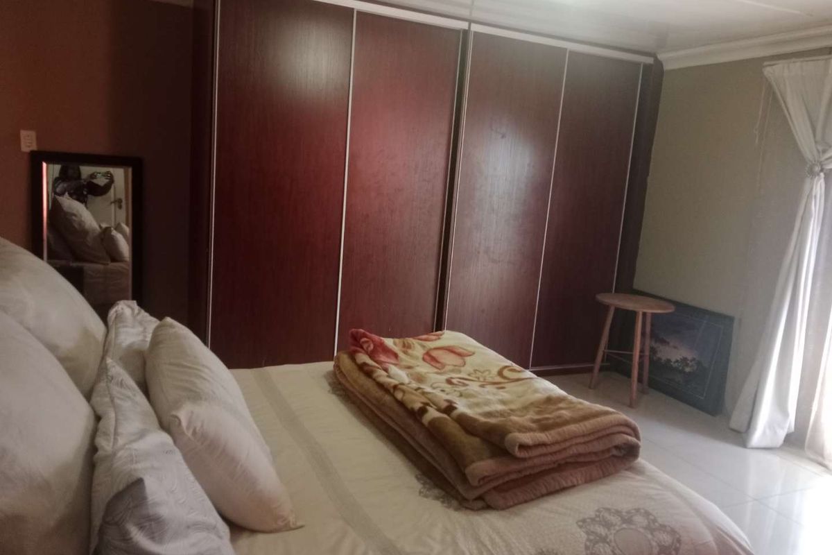 A bedroom featuring built-in floor-to-ceiling wooden wardrobes and tiled flooring, providing ample storage space.