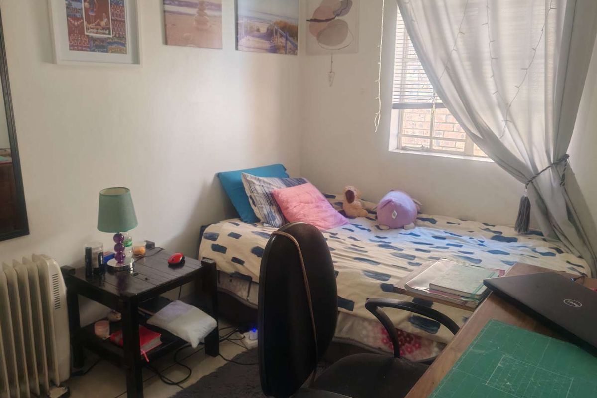 A functional bedroom featuring tiled flooring and a window with natural light, suitable for a comfortable living space.