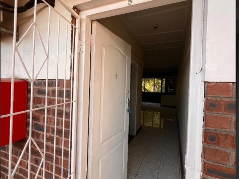 Entrance area featuring a security gate, tiled flooring, and direct access into the apartment hallway.