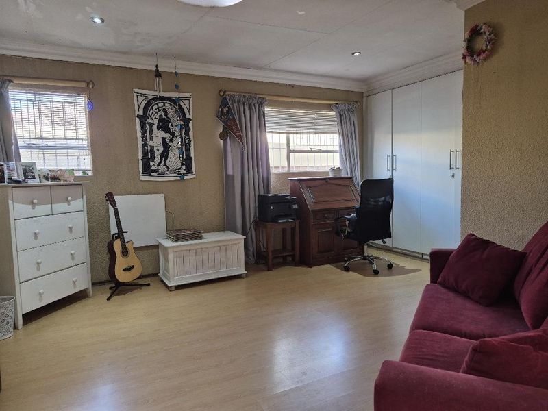 Spacious bedroom featuring laminate flooring, built-in cupboards, and recessed downlighting, offering a versatile layout for sleeping or study arrangements.