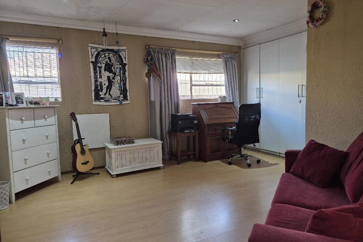 Spacious bedroom featuring laminate flooring, built-in cupboards, and recessed downlighting, offering a versatile layout for sleeping or study arrangements.