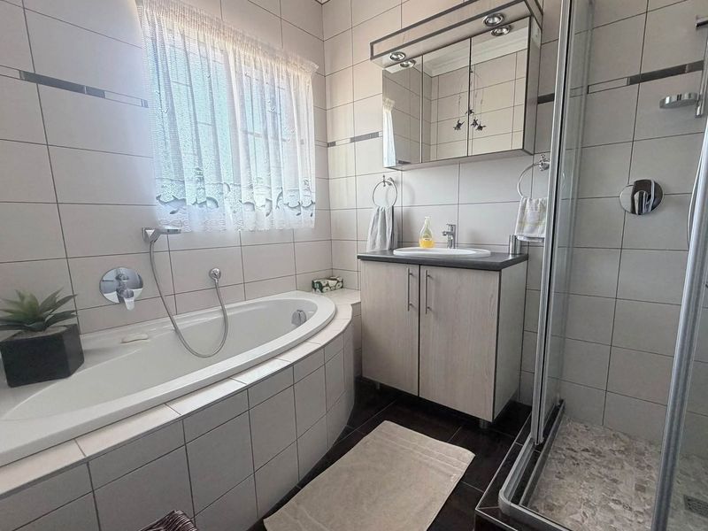 A well-maintained bathroom featuring a built-in bathtub, separate shower enclosure, and a modern vanity cabinet with integrated storage.
