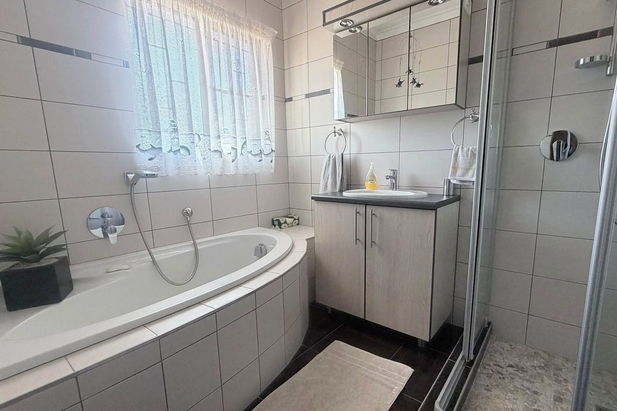 A well-maintained bathroom featuring a built-in bathtub, separate shower enclosure, and a modern vanity cabinet with integrated storage.