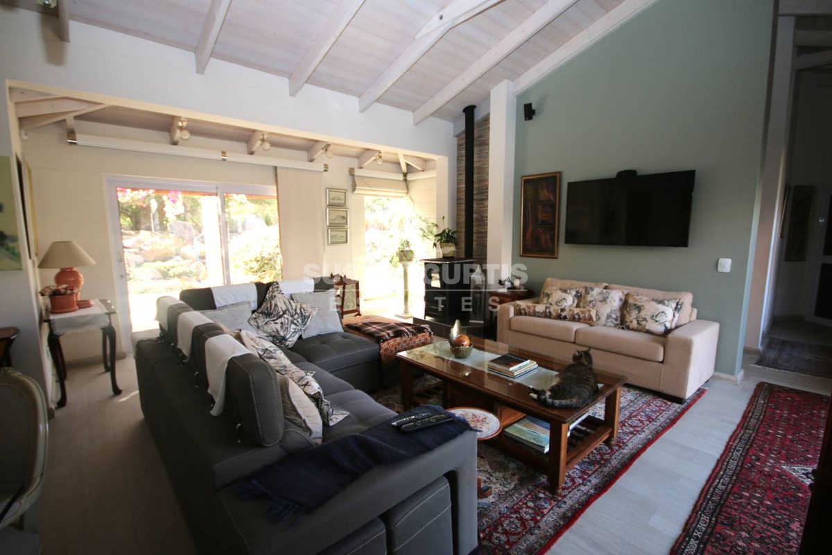 Spacious living room featuring high vaulted ceilings with exposed timber beams, a cozy fireplace, and large sliding doors providing access to the garden.