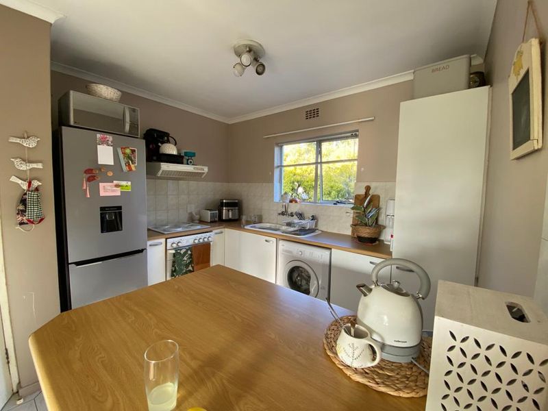 Functional kitchen featuring built-in cabinetry, laminate countertops, tiled backsplash, integrated washing machine, and a built-in oven with extractor fan.