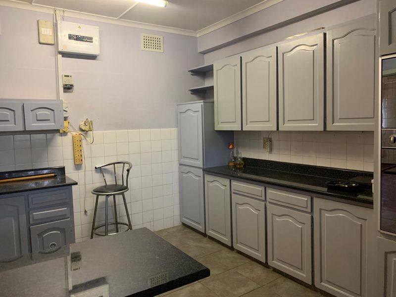 A functional kitchen featuring built-in cabinetry, dark countertops, and tiled backsplash, offering potential for modernization and aesthetic updates.